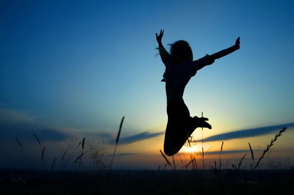 Sylwetka o dziewczynie skaczącej przez zachód słońca Zdjęcie Stockowe