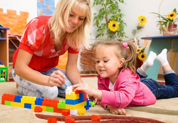 Professor e criança estão brincando com tijolos — Fotografia de Stock
