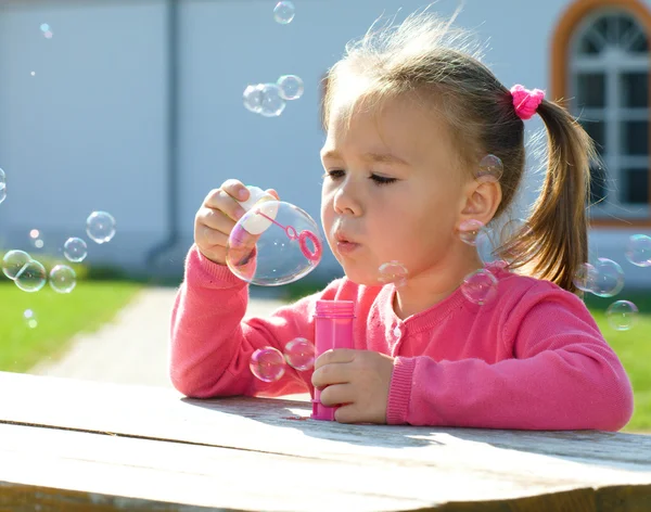 小さな女の子が石鹸の泡を吹いています。 — ストック写真