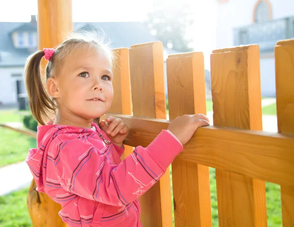 Carina bambina è in piedi vicino a una recinzione — Foto Stock