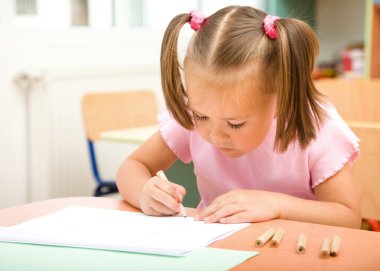 Little girl is drawing with color pencils clipart