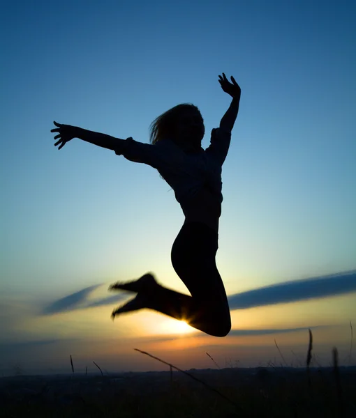 Silhouette of a girl jumping over sunset — Stock Photo, Image