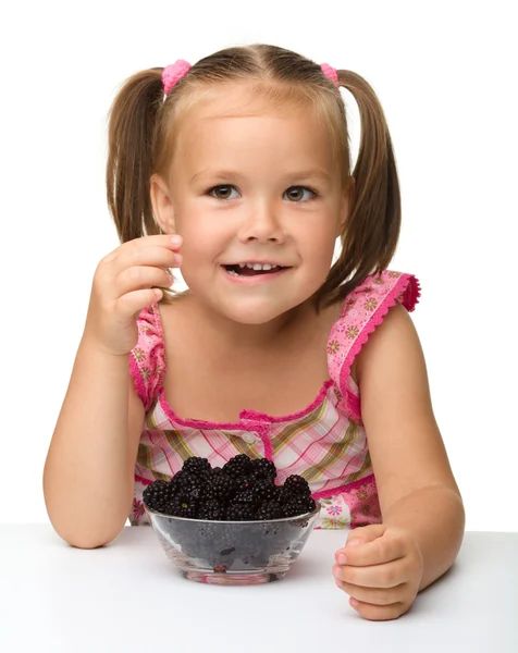Веселая маленькая девочка ест ежевику — стоковое фото