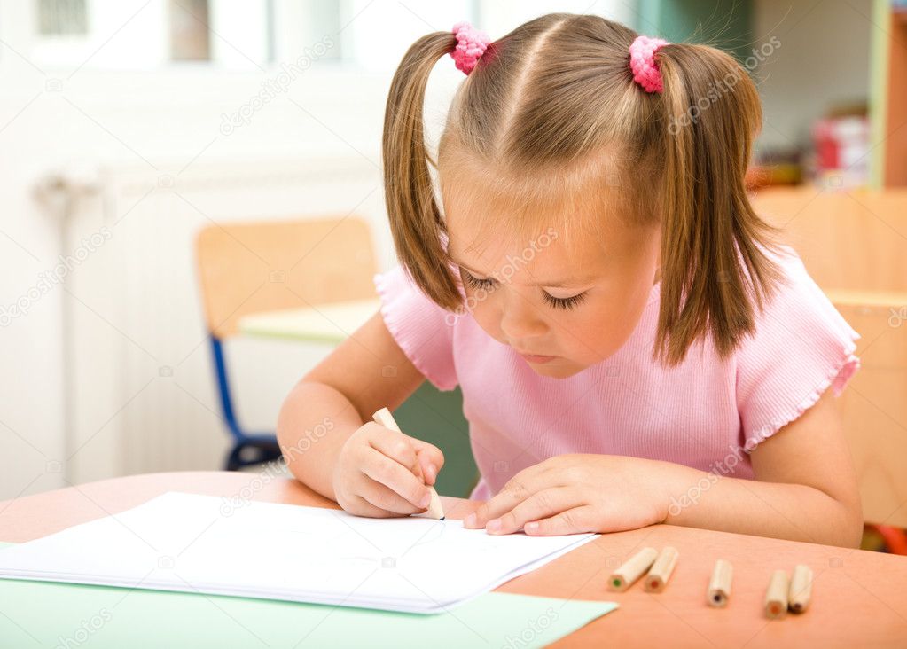 Little girl is drawing with color pencils