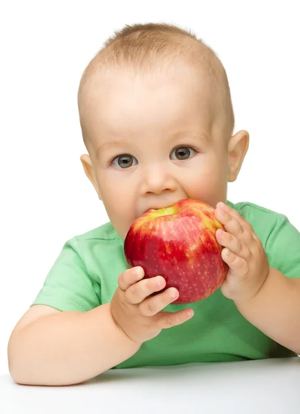 小さな子供は赤いリンゴを食べています。 — ストック写真