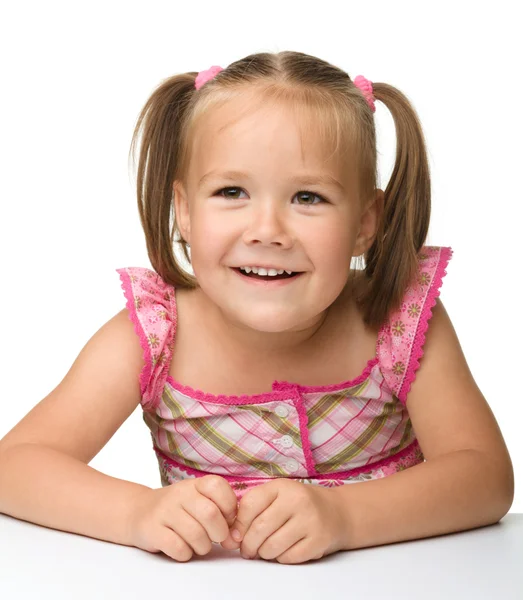 Szczęśliwa dziewczynka siedzi przy stole — Zdjęcie stockowe