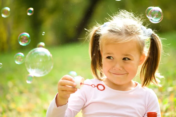 Little girl is blowing a soap bubbles — Stock Photo, Image