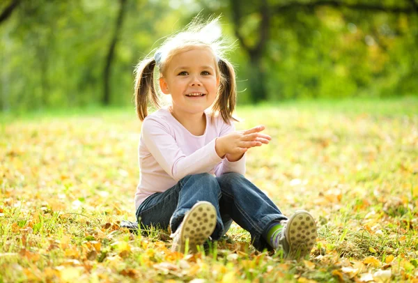 小さな女の子は緑の牧草地に座っています。 — ストック写真