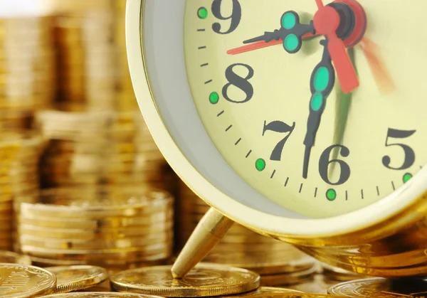 El tiempo es dinero - marcación del reloj y monedas de oro Imagen de stock