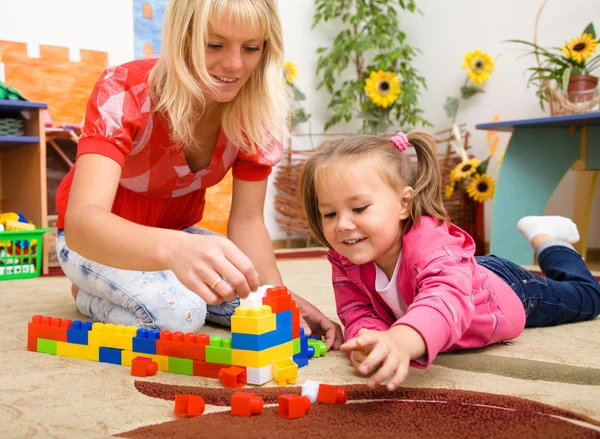 Professor e criança estão brincando com tijolos — Fotografia de Stock