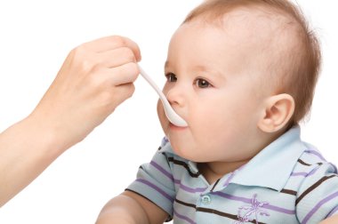 Little boy is being feed by his mother clipart