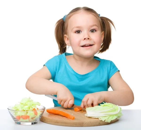 Маленька дівчинка ріже моркву для салату — стокове фото