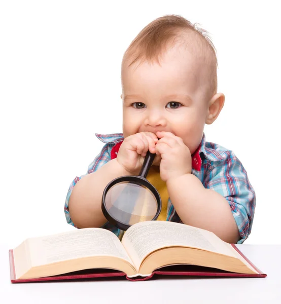 Criança brinca com livro e lupa — Fotografia de Stock