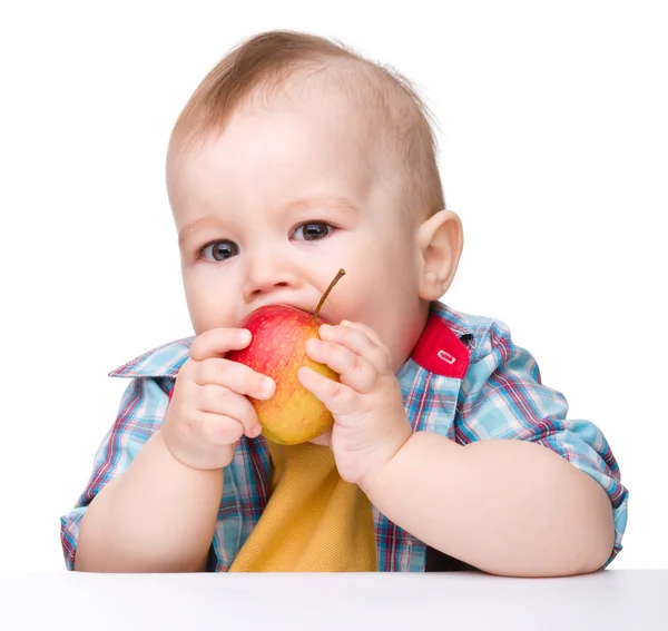 Pequeño niño está comiendo manzana roja — Foto de Stock