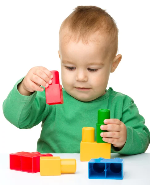 Kisfiú játszik a tégla épület — Stock Fotó