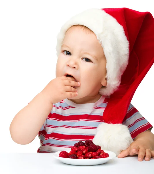 Ładny chłopczyk jeść jagody santa kapeluszu — Zdjęcie stockowe