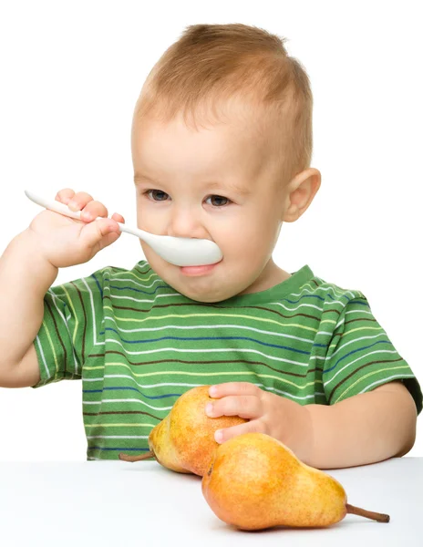 Cute little boy with pears is biting spoon — Stock Photo, Image