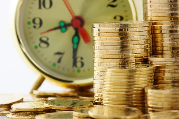 El tiempo es dinero - marcación del reloj y monedas de oro Fotos de stock