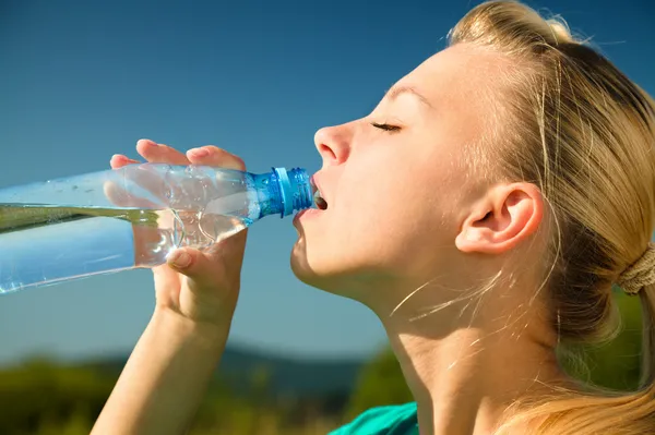 Young woman is drinking water outdoors — Stock Photo, Image