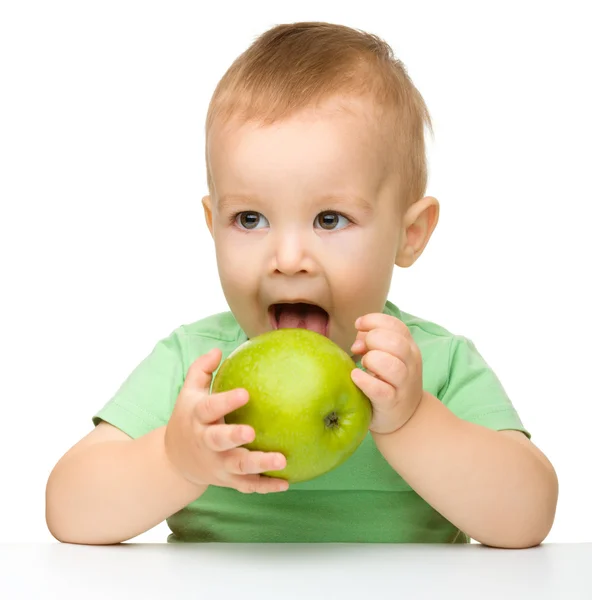 Little child is eating green apple Stock Photo