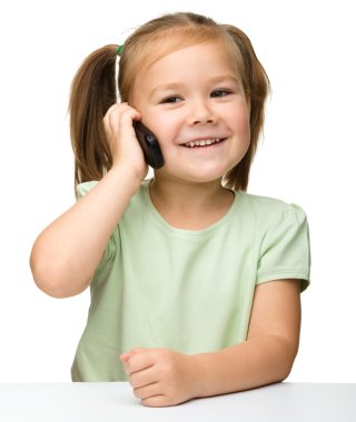 Tatlı küçük kız cep telefonuyla konuşuyor.