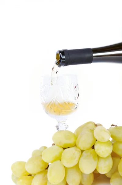 Vinho branco derramando no cálice e uvas isoladas em branco — Fotografia de Stock