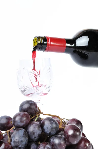 Rode wijn, gieten in de goblet en druiven geïsoleerd in wit — Stockfoto