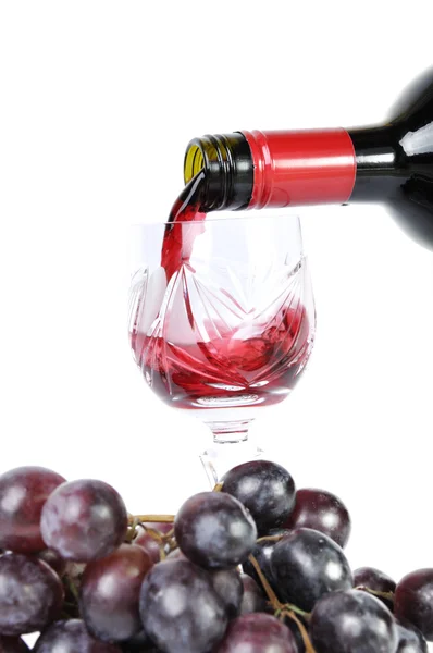 Red wine pouring in the goblet and grapes isolated in white — Stock Photo, Image