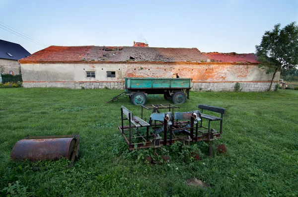 Old, rusty, farming equipment, trailer and an old builing — Stock Photo, Image