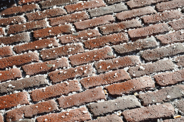 A red brick walkway covered in salt in bright sunlight