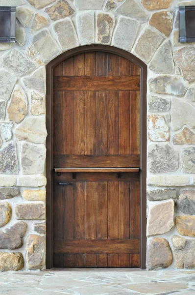 Dřevěné dveře na kamenné zdi Stock Snímky