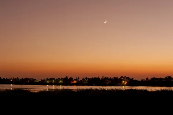 Sunset over a river with the moon — Stock Photo, Image