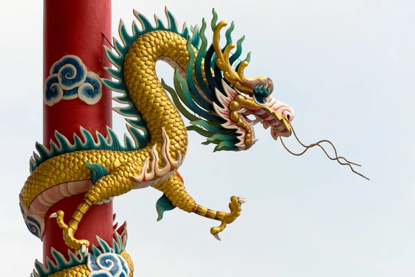 Золотой китайский дракон обернулся вокруг красного полюса — стоковое фото