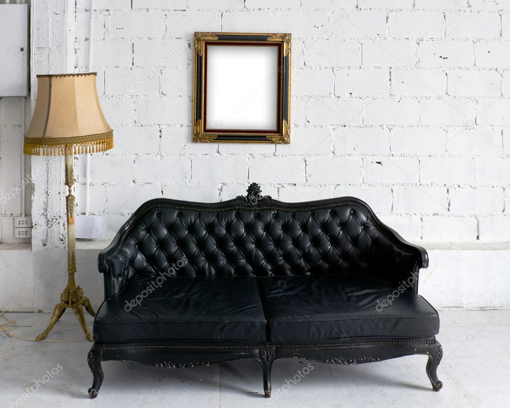 Old black leather sofa with lamp and wood picture frame