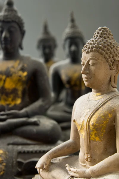 Jeden bílý kámen buddha a tři černé soše — Stock fotografie