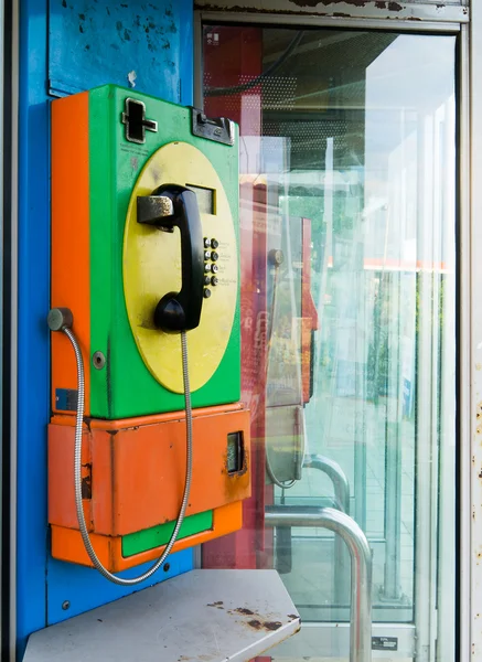 Оранжевый зеленый и желтый общественный телефон — стоковое фото