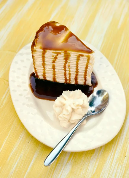 Crème taart gegarneerd met karamel en lepel — Stockfoto