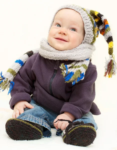 Söt baby boy i stickad handgjorda mössa, halsduk och stövletter är sitt — Stockfoto