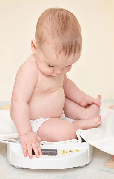 Söt baby kontrollera egen vikt på hem skalor — Stockfoto