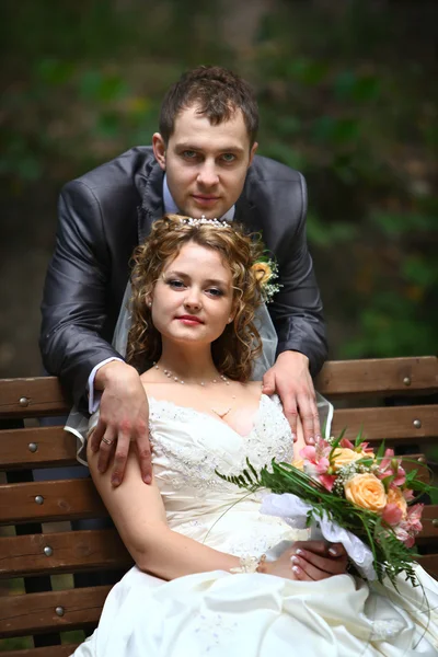 Sposa e sposo seduti sulla panchina — Foto Stock