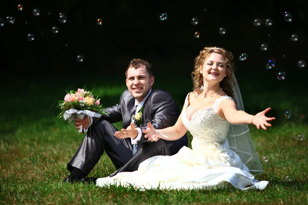 Bride and groom catching soap bubbles — Stock Photo, Image