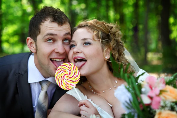 Bride and groom with lollypop — Zdjęcie stockowe