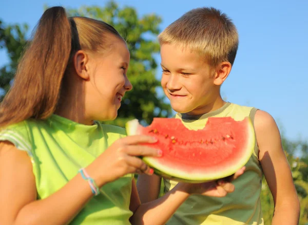 Jong meisje en jongen eten watermeloen — Stockfoto