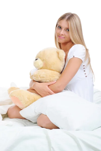 泰迪熊的拥抱在床上的年轻女子 在白色背景上孤立 — 图库照片