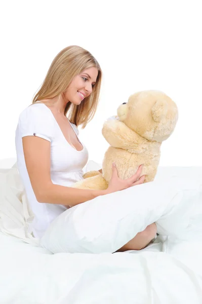 泰迪熊的拥抱在床上的年轻女子 在白色背景上孤立 — 图库照片