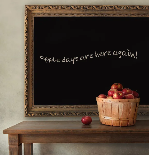 Fresh apples on wooden table with blackboard — Stock Photo, Image