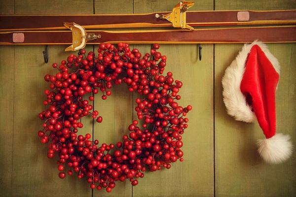 Red wreath with Santa hat hanging on rustic wall — Stock Photo, Image