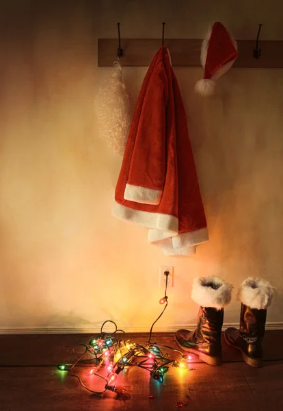 Santa κοστούμι που κρέμονται στο άγκιστρο παλτό με φώτα των Χριστουγέννων — Φωτογραφία Αρχείου