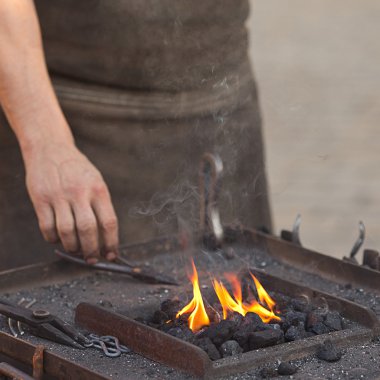 Embers, fire, smoke, tools and the hands of a blacksmith clipart