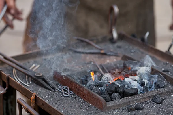 Brasas, fuego, humo, herramientas y las manos de un herrero — Foto de Stock